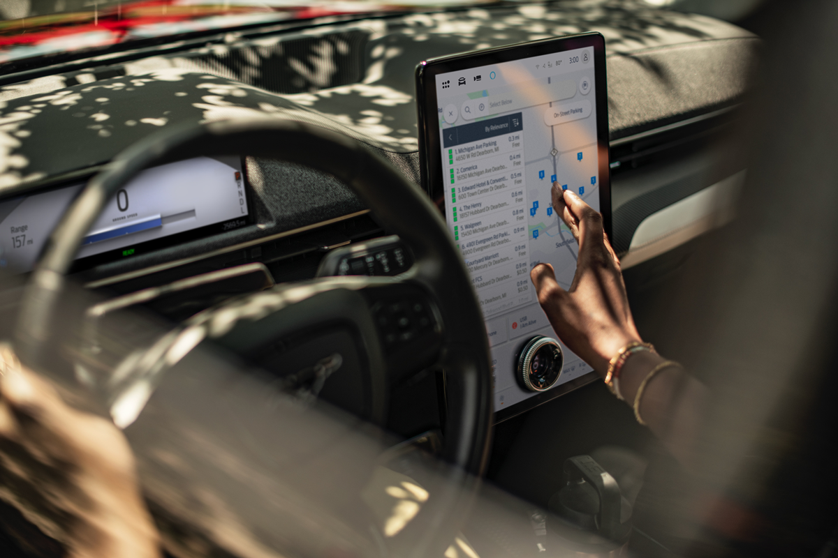 A person in a Mustang Mach-E using the center console tablet.